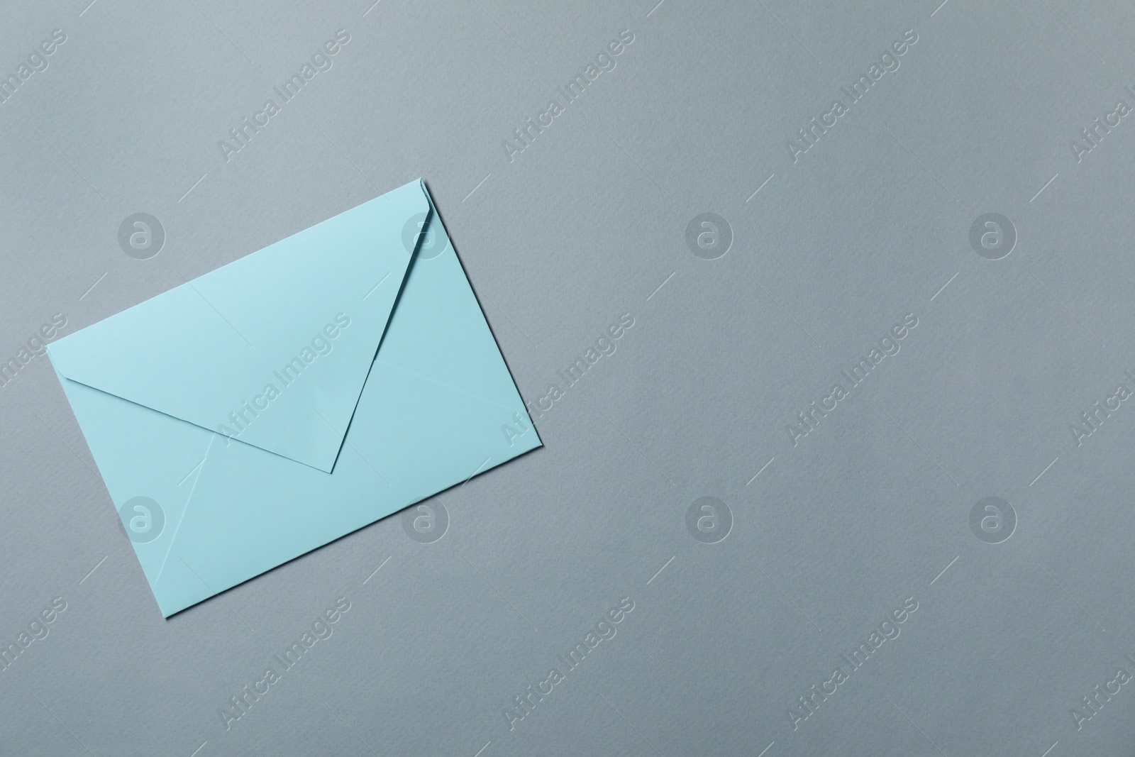 Photo of Letter envelope on grey background, top view. Space for text