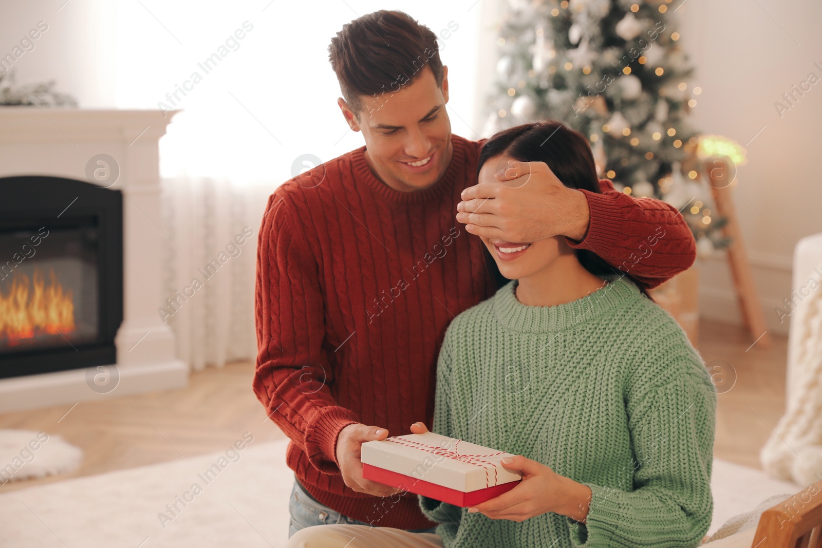 Photo of Boyfriend giving Christmas gift box to his girlfriend at home