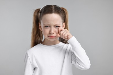 Portrait of sad girl on light grey background