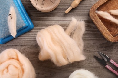 Photo of Felting wool and different tools on wooden table, flat lay