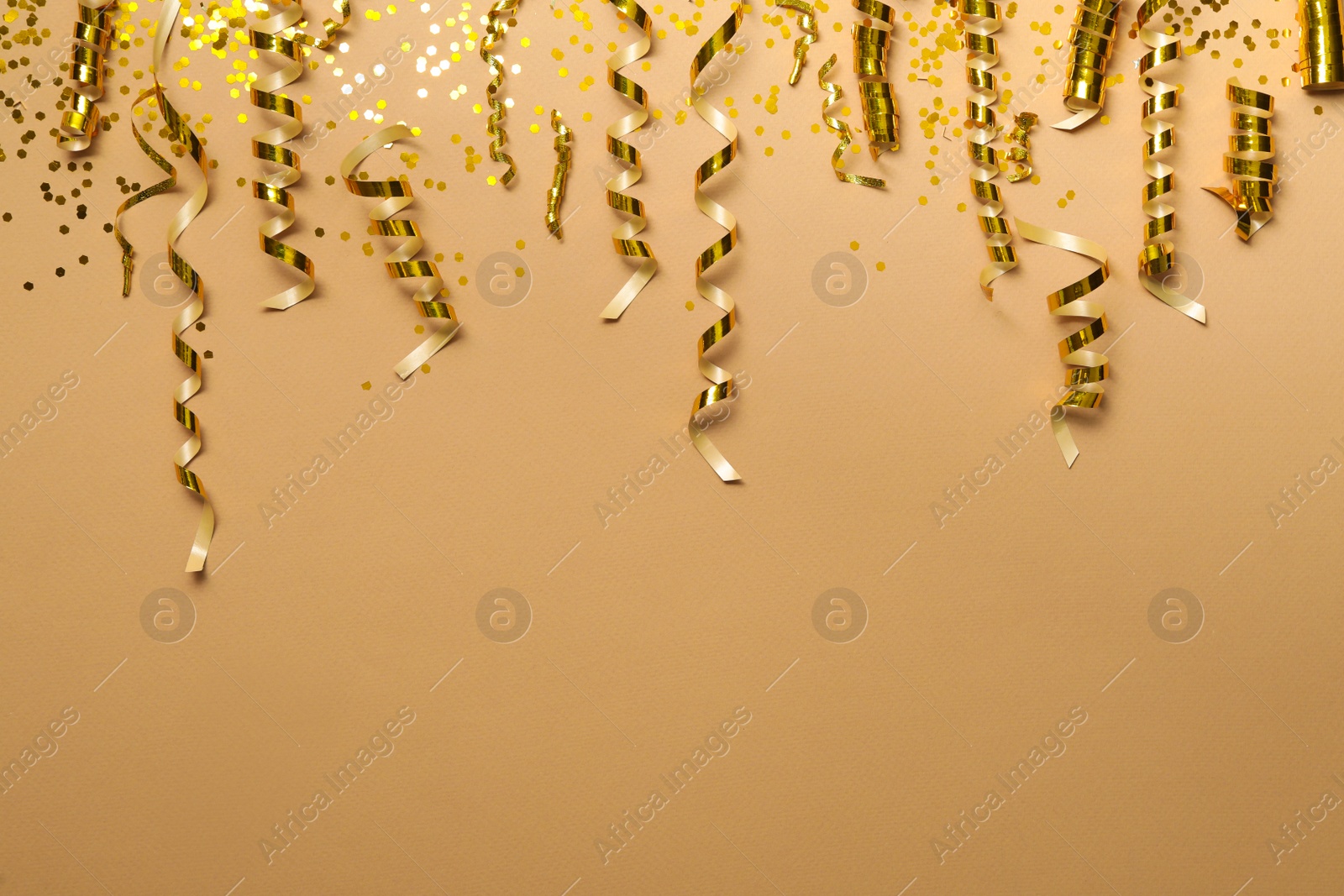 Photo of Shiny golden serpentine streamers and confetti on beige background, flat lay. Space for text