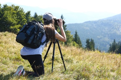 Photo of Woman taking photo of mountain landscape with modern camera on tripod outdoors