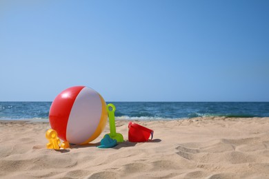 Photo of Many different sand toys and beach ball near sea, space for text