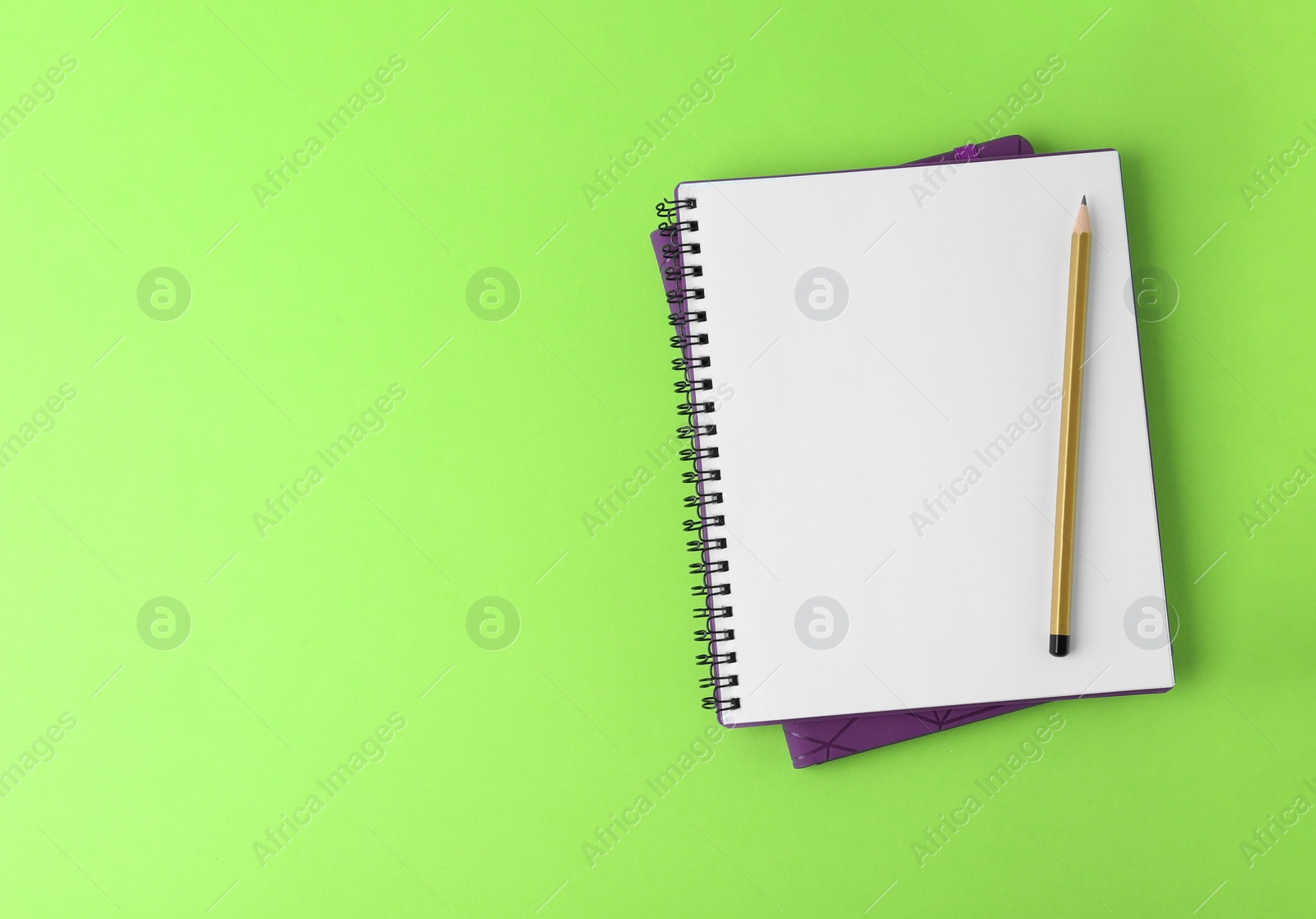 Photo of Notebooks with pencil on light green background, top view. Space for text