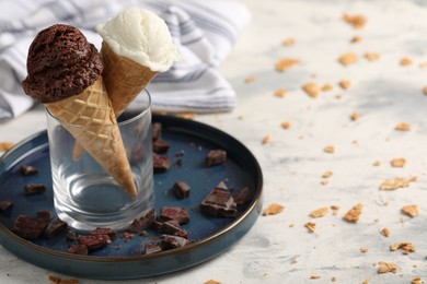 Photo of Tasty ice cream scoops in waffle cones and chocolate crumbs on light table, closeup. Space for text