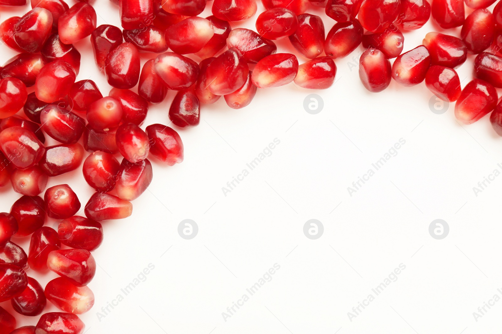 Photo of Many ripe juicy pomegranate grains on white background, flat lay. Space for text