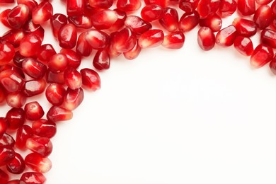 Many ripe juicy pomegranate grains on white background, flat lay. Space for text