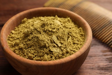 Photo of Bowl of henna powder on wooden table, closeup
