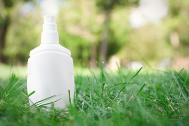 Bottle of insect repellent spray on grass. Space for text