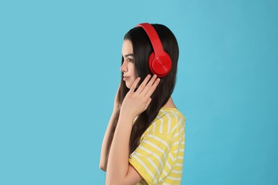 Photo of Teenage girl listening music with headphones on light blue background