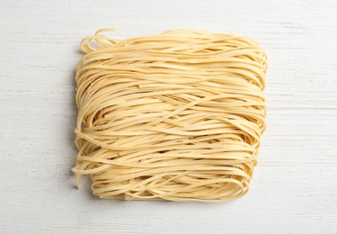 Photo of Block of quick cooking noodles on wooden background, top view