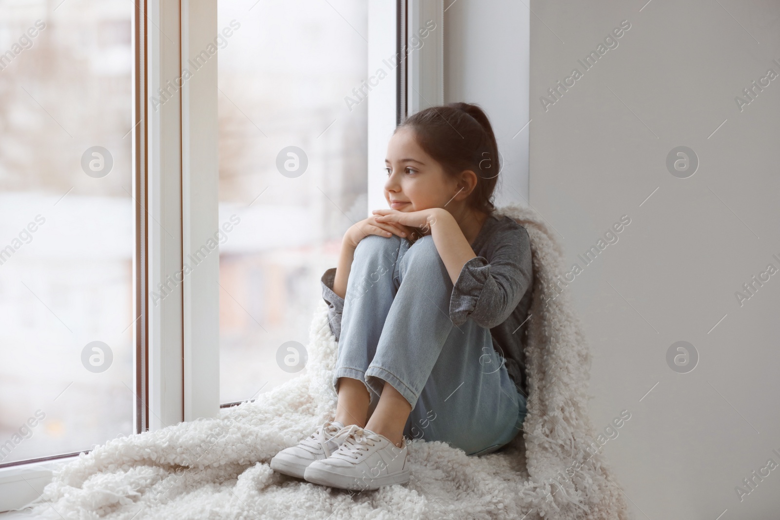 Photo of Cute little girl with plaid resting near window