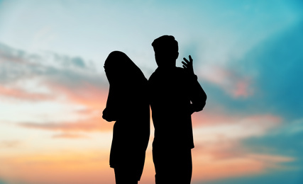 Image of Silhouettes of arguing couple against sunset sky with clouds. Relationship problems