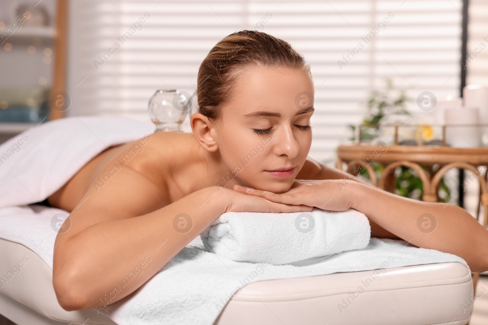 Photo of Cupping therapy. Woman with glass cup on massage couch in spa salon