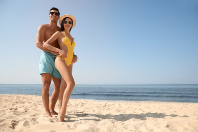 Photo of Happy couple on sunny beach at resort. Space for text