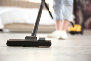 Photo of Young woman using vacuum cleaner at home, closeup