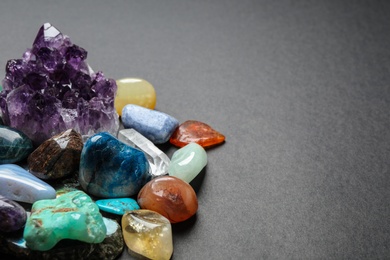 Photo of Different gemstones on dark table, space for text