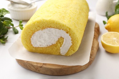 Delicious cake roll, lemons and mint on white table, closeup