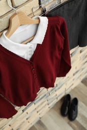 Photo of School uniform for girl hanging on brick wall, closeup