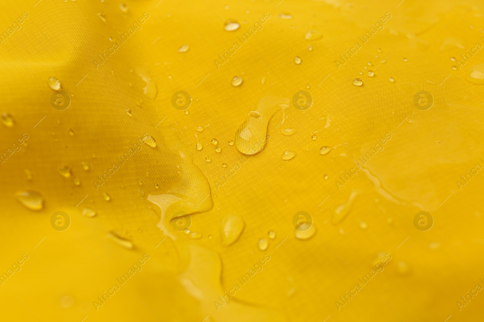 Photo of Yellow waterproof fabric with water drops as background, closeup