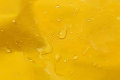Photo of Yellow waterproof fabric with water drops as background, closeup