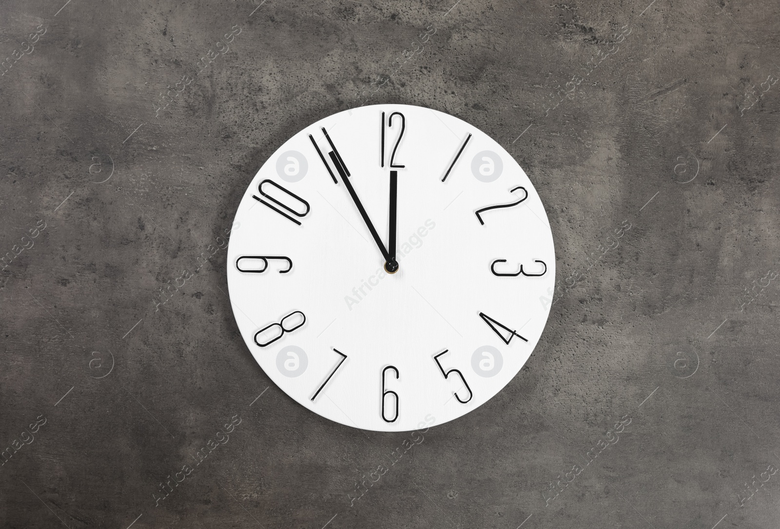 Photo of Stylish analog clock hanging on grey wall. New Year countdown
