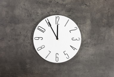 Stylish analog clock hanging on grey wall. New Year countdown