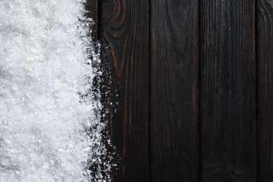 Snow and space for text on wooden background, top view. Christmas time