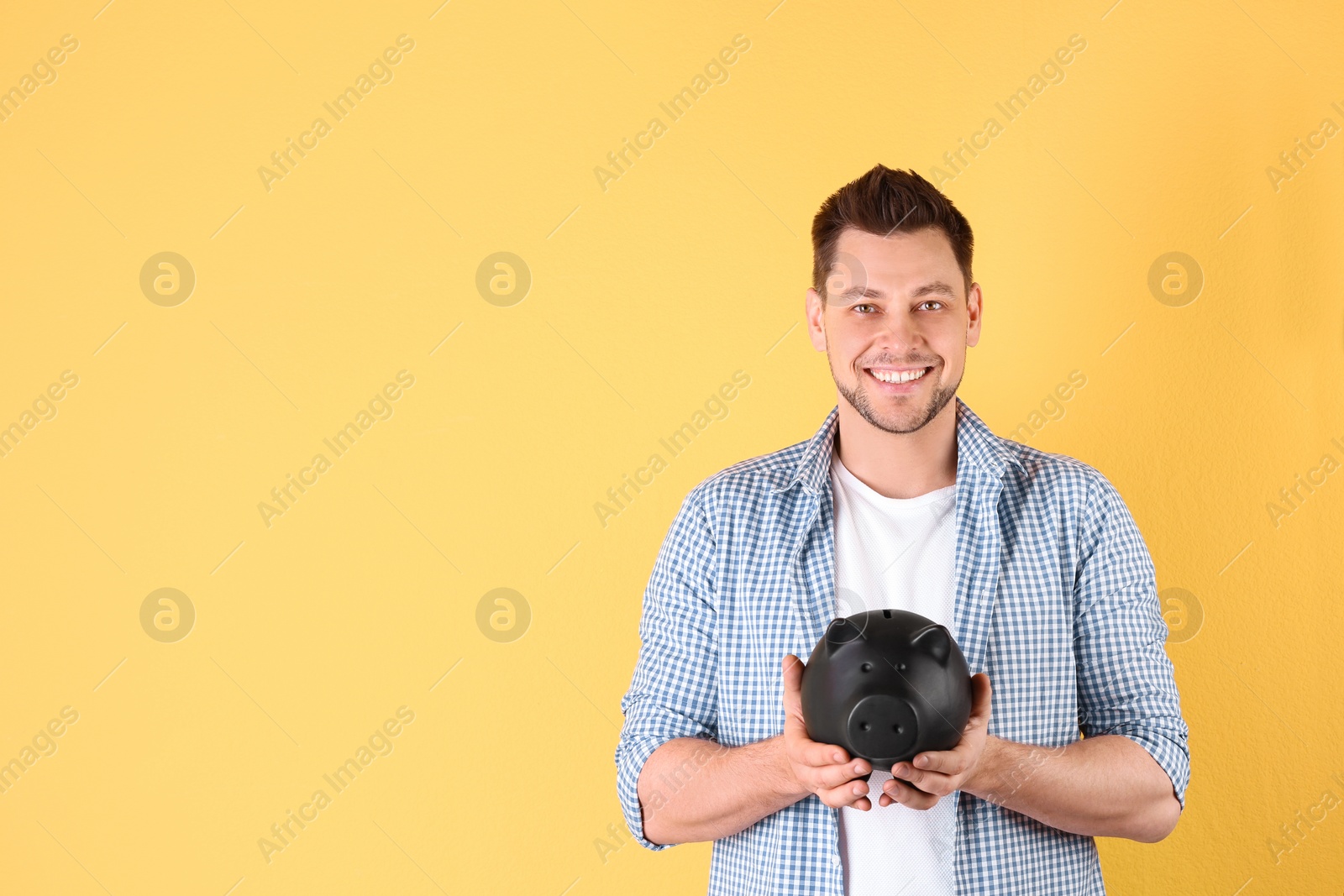 Photo of Man with piggy bank on color background. Space for text