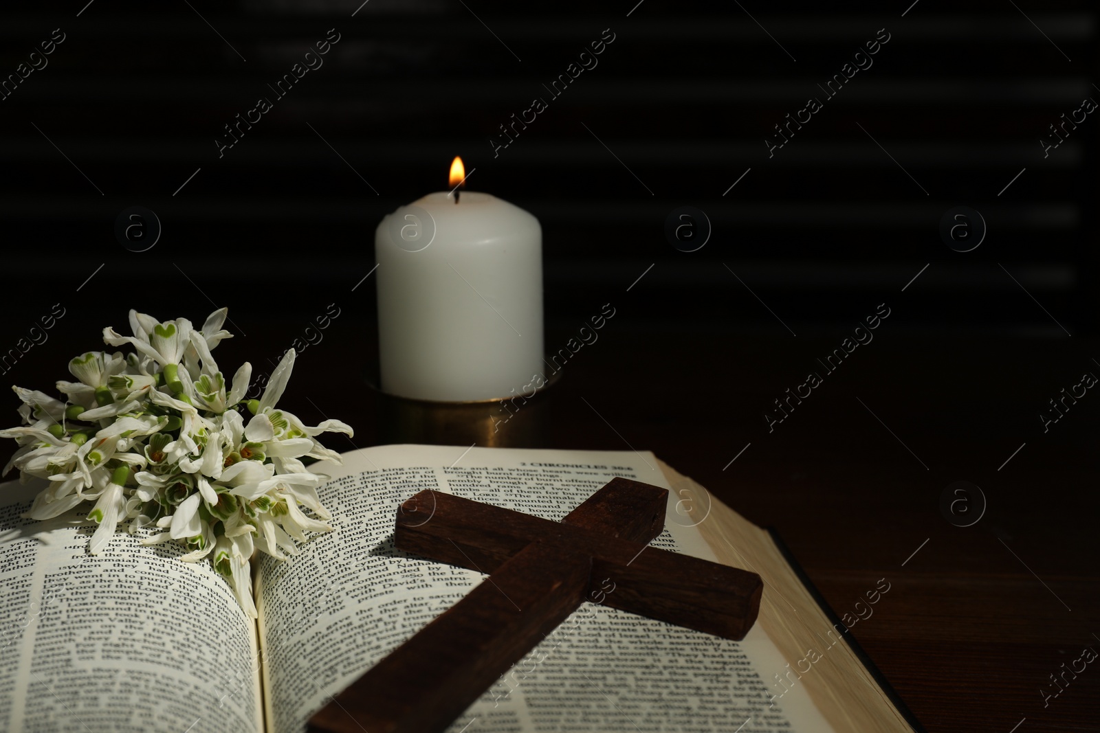 Photo of Church candle, Bible, cross and flowers on wooden table