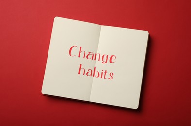 Photo of Notebook with text Change Habits on red background, top view