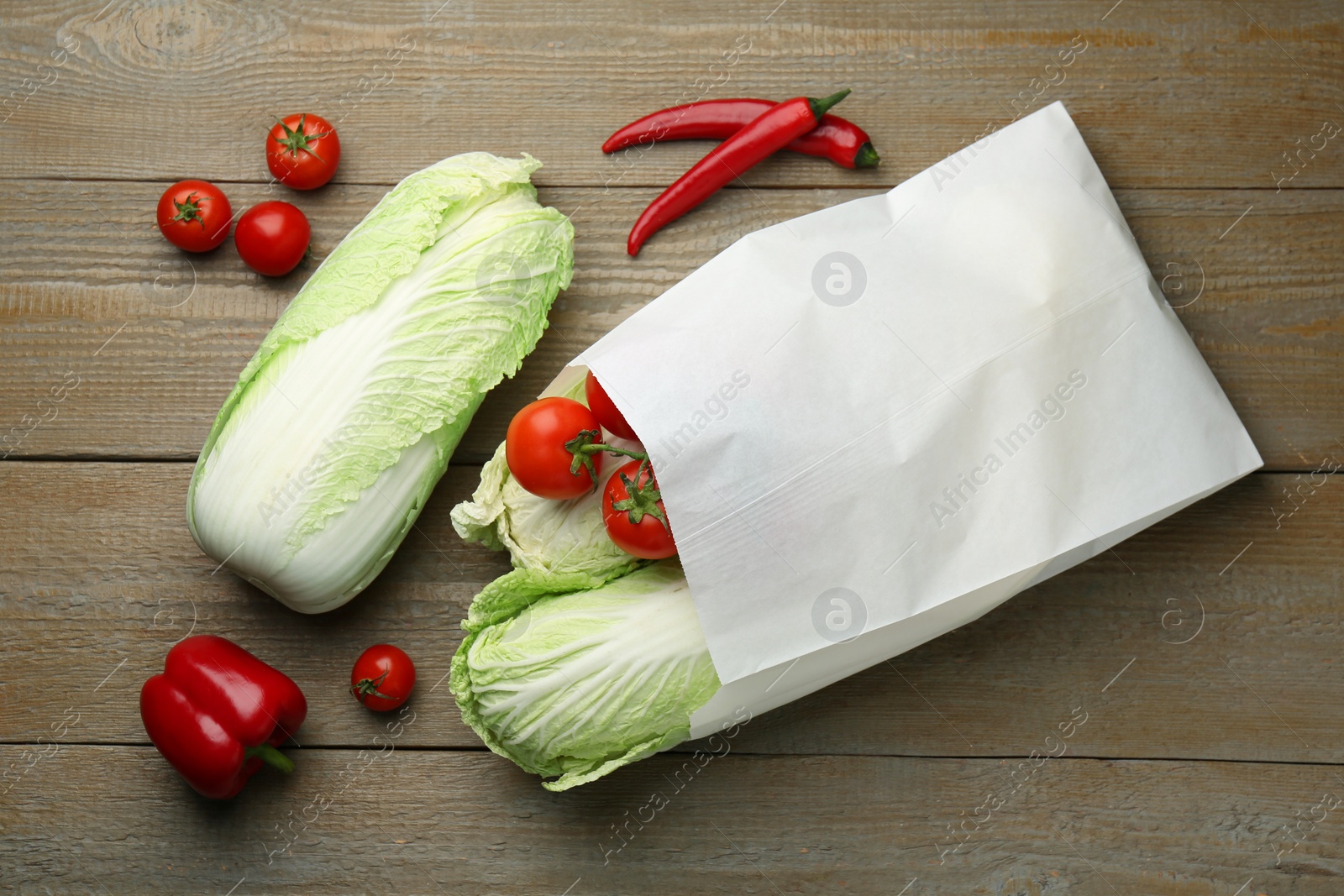 Photo of Fresh Chinese cabbages, tomatoes and peppers on wooden table, flat lay