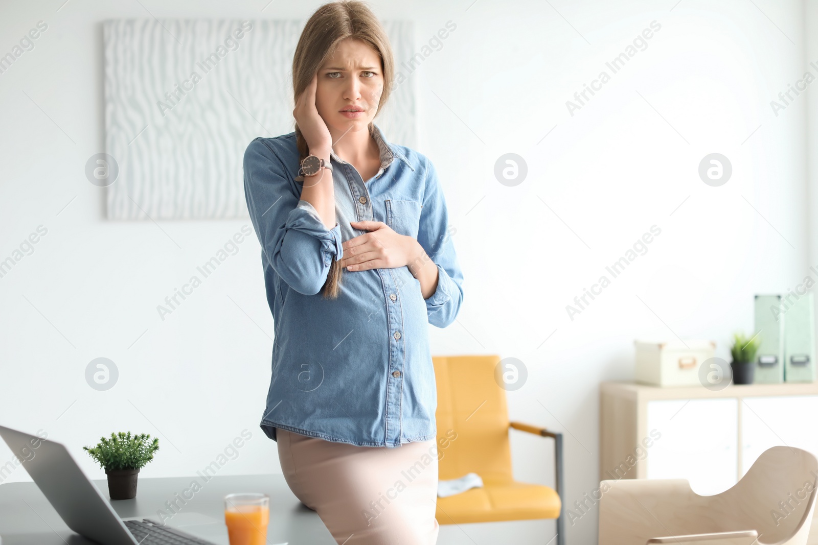 Photo of Pregnant woman suffering from headache at workplace