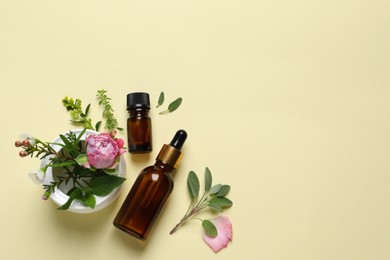 Photo of Bottles of essential oils, different herbs and rose flower on beige background, flat lay. Space for text
