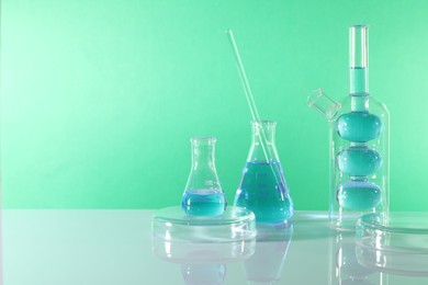 Photo of Laboratory analysis. Different glassware on table against green background, space for text