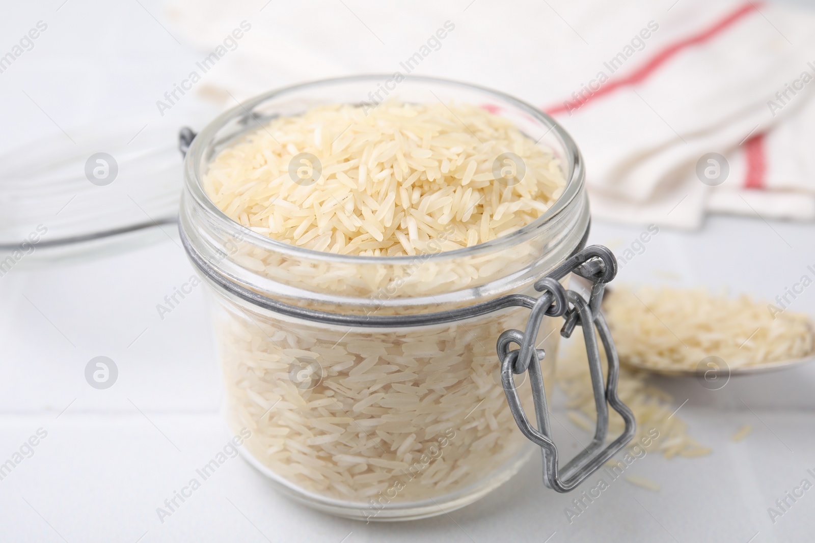 Photo of Raw rice in glass jar on white table, closeup