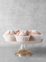 Cake stand with tasty muffins on light grey table