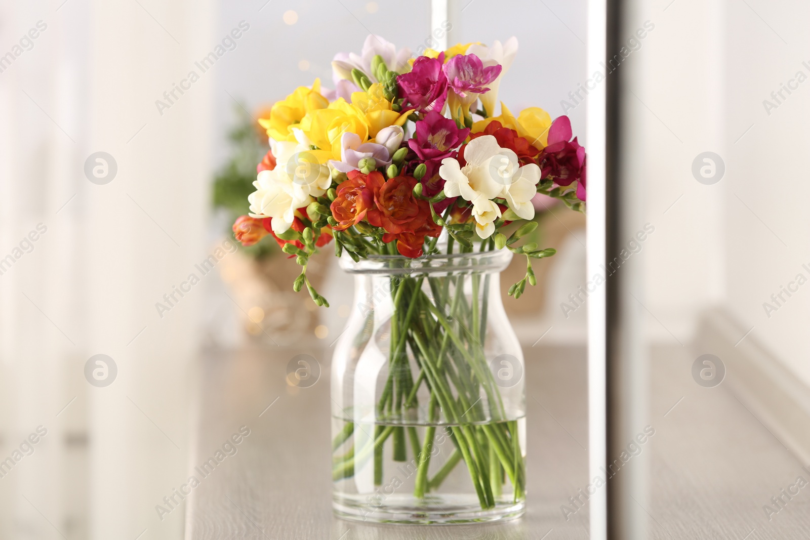 Photo of Beautiful spring bright freesia flowers in vase on table