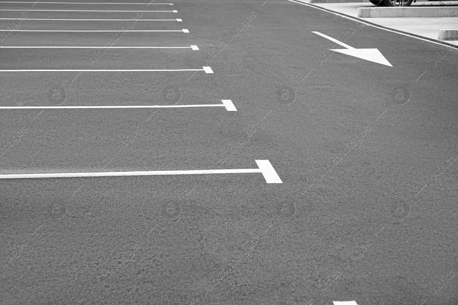 Photo of White painted car parking lots and arrow marking on asphalt outdoors