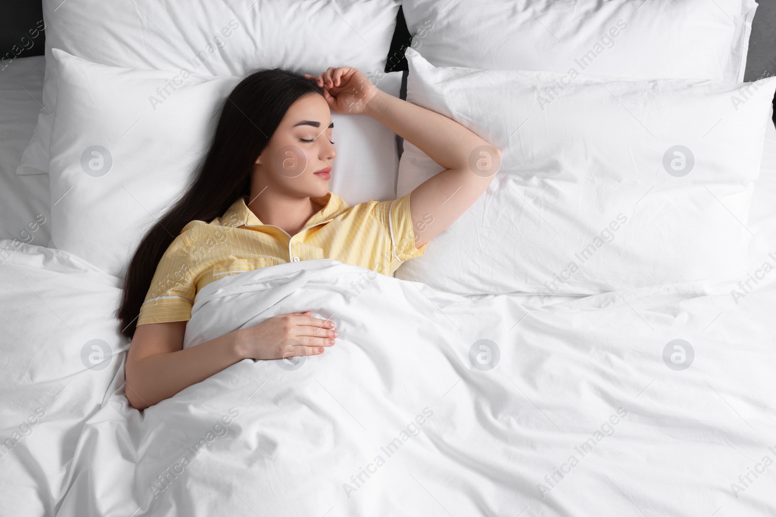 Photo of Beautiful young woman sleeping in soft bed, above view