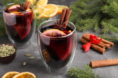 Photo of Aromatic mulled wine and ingredients on grey table, closeup