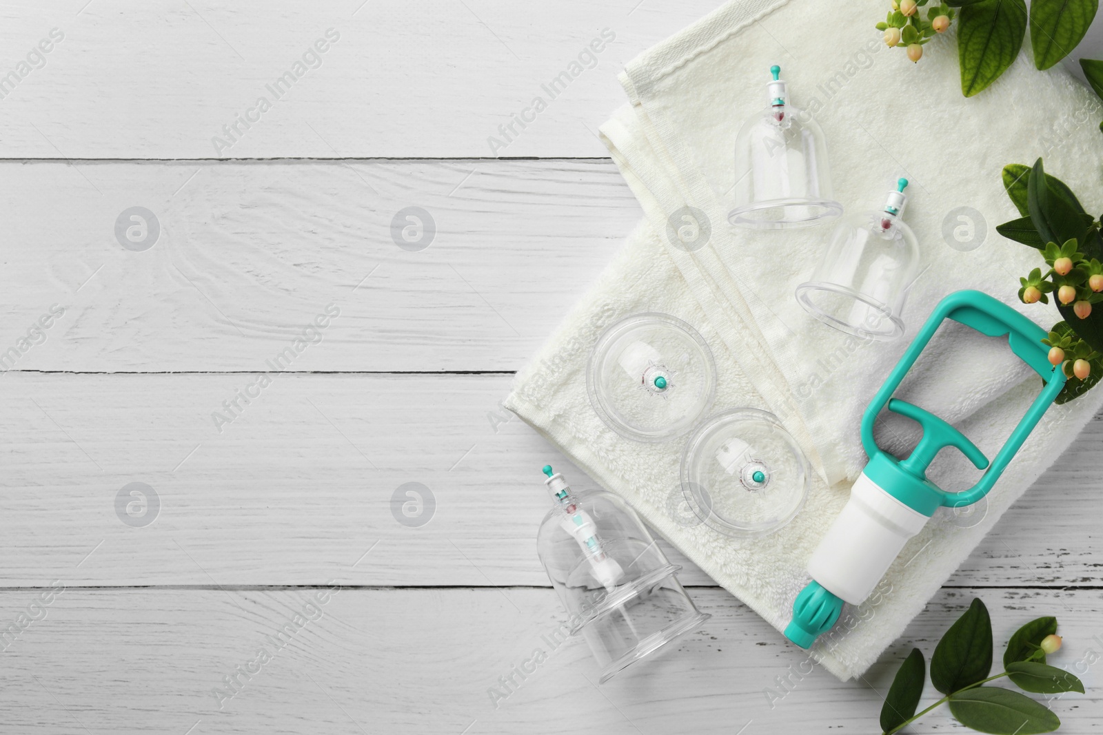 Photo of Cupping therapy. Plastic cups, hand pump, towels and hypericum perforatum berries on white wooden table, flat lay. Space for text