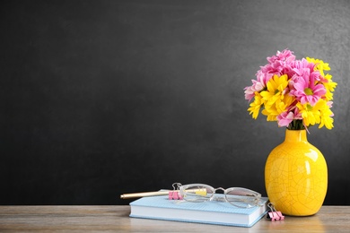 Photo of Bouquet of flowers and notebooks with eyeglasses on table. Teacher day celebration