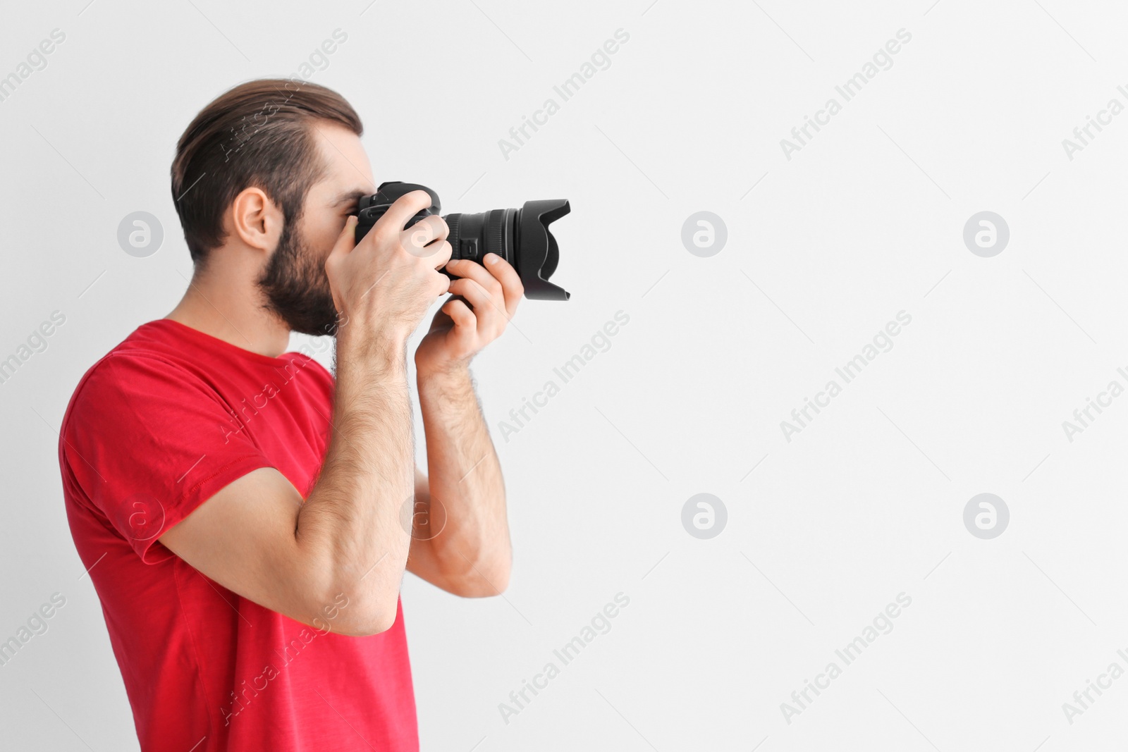 Photo of Young photographer with professional camera on white background