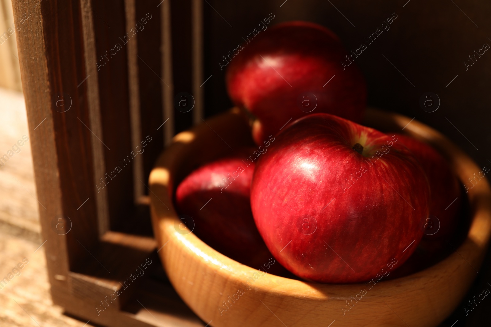 Photo of Fresh red apples in bowl on wooden table, closeup