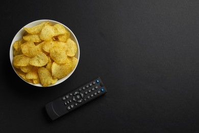 Photo of Modern tv remote control and chips on black background, flat lay. Space for text