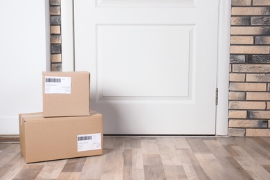 Photo of Cardboard parcel boxes on floor near apartment entrance. Mockup for design