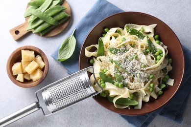 Delicious pasta with green peas and ingredients on grey table, flat lay