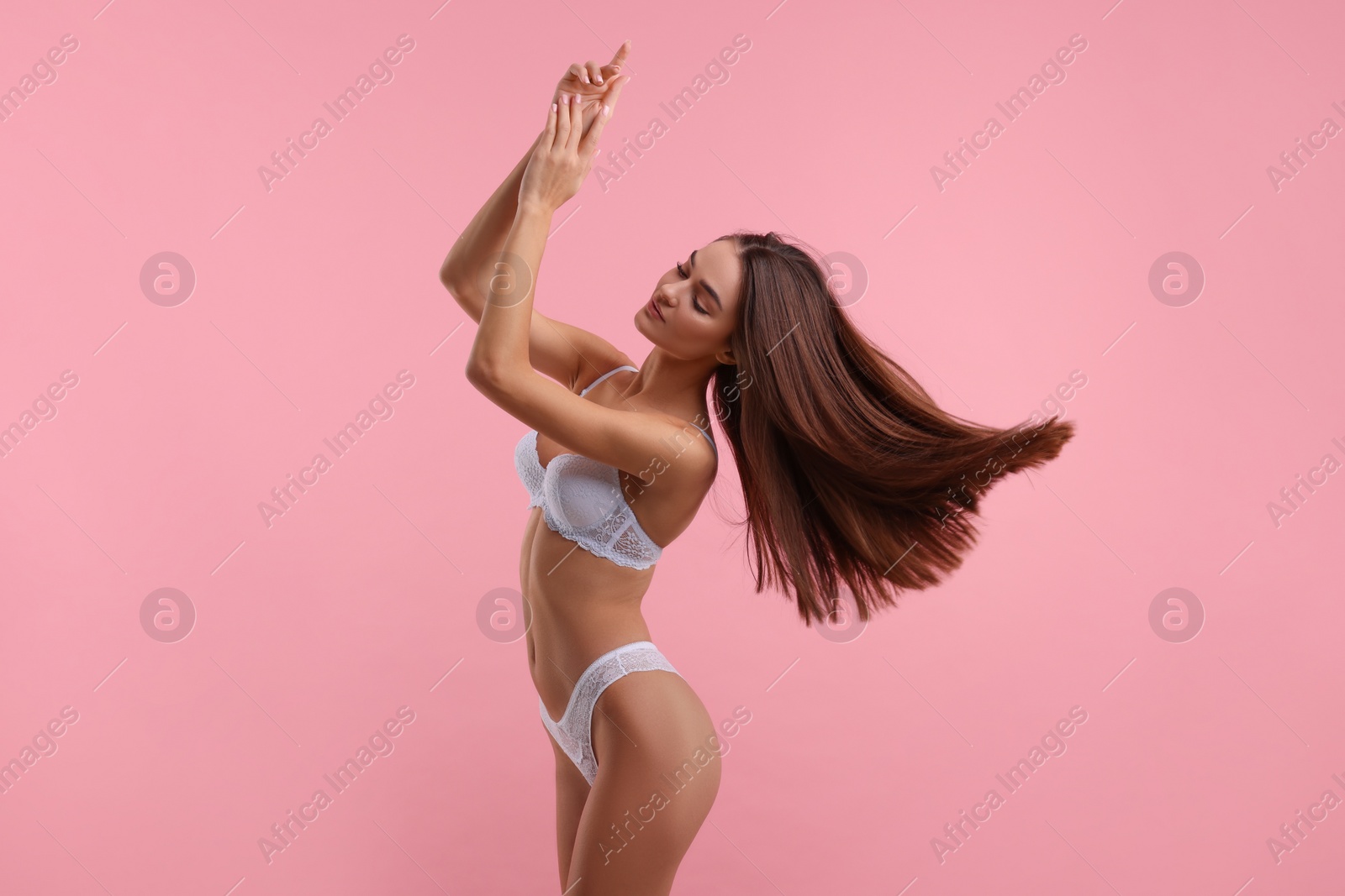 Photo of Young woman in elegant white underwear on pink background