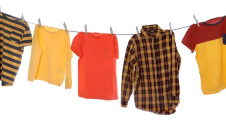 Different bright clothes drying on washing line against white background